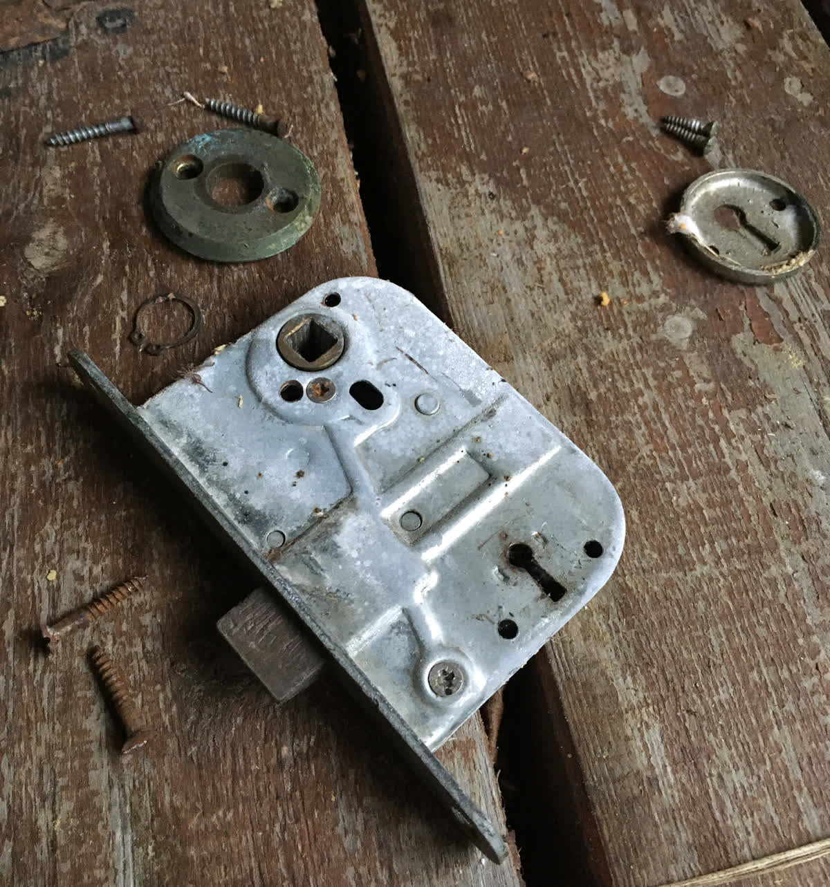Ett lås med lösa skruvar utlagt på ett golv.
